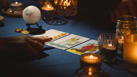 Close-Up-Of-Woman-Giving-Tarot-Card-Reading-To-Man-On-Candlelit-Table